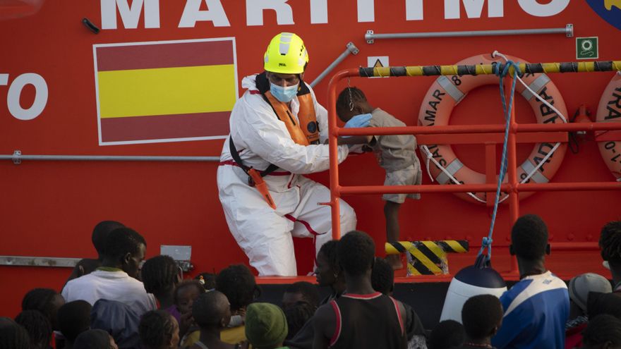 Archivo - Una persona de Salvamento Marítimo ayuda a un menor, en el Puerto de la Restinga
