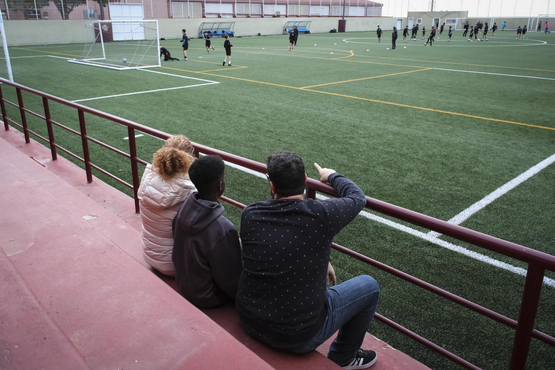 Adú, con sus padres de acogida, en el campo en el que entrena.