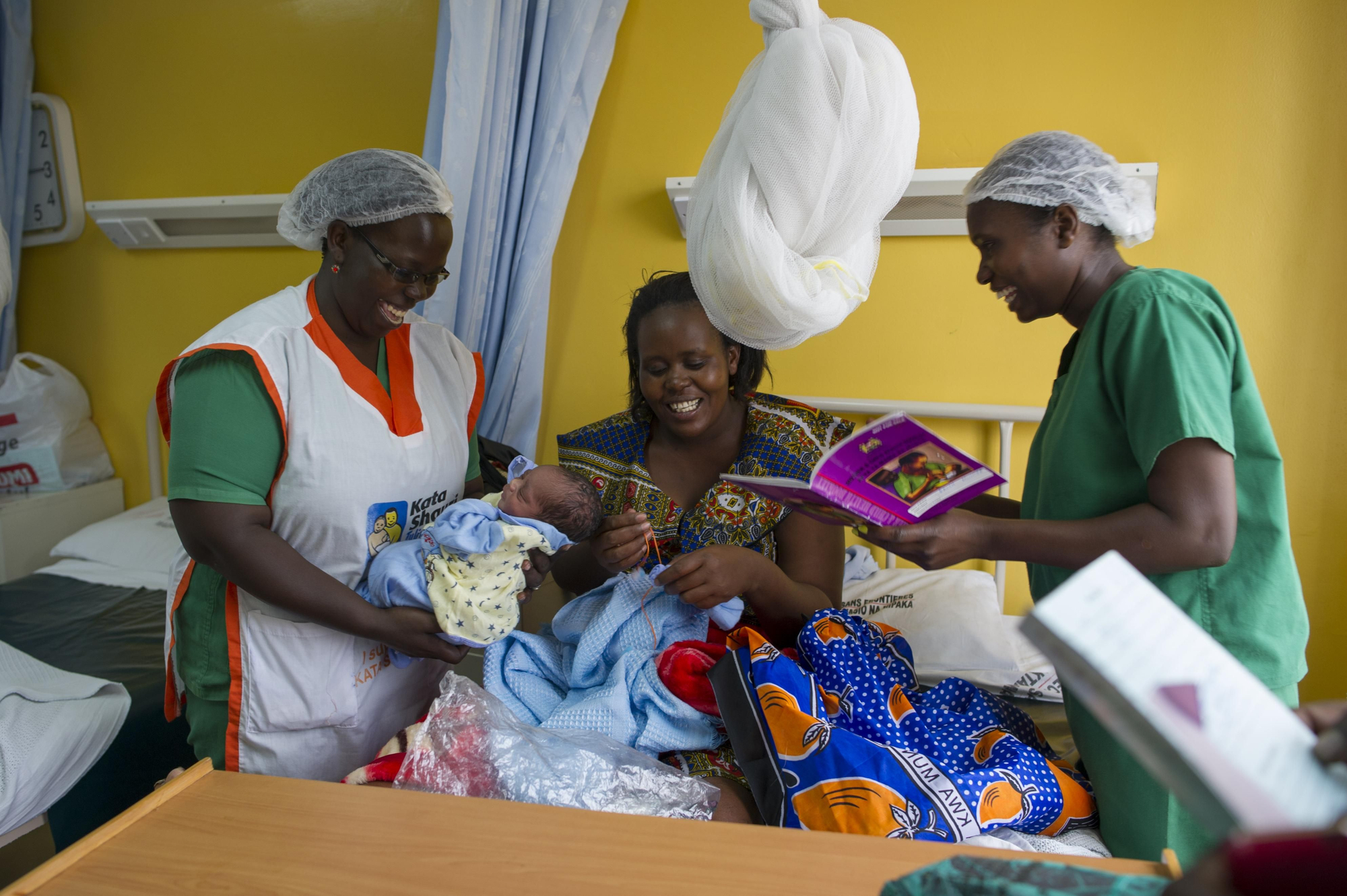 Nancy Thairu (izquierda) y Grace Kinyua (derecha), ambas matronas de MSF, atienden a Mary Wambui (35) que acana de dar a luz a su quinto hijo, John Mutua. Las matronas comprueban que los bebés se adapten bien a lactancia materna, y se encuentren en buen estado antes de dar el alta a sus madres. Fotografía: Phil Moore