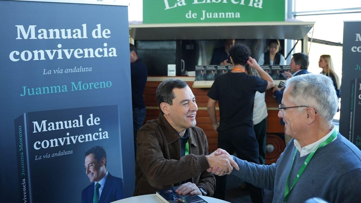 El presidente andaluz, Juan Manuel Moreno, firma ejemplares de su libro 'Manual de convivencia', en el hall del congreso del PP andaluz.