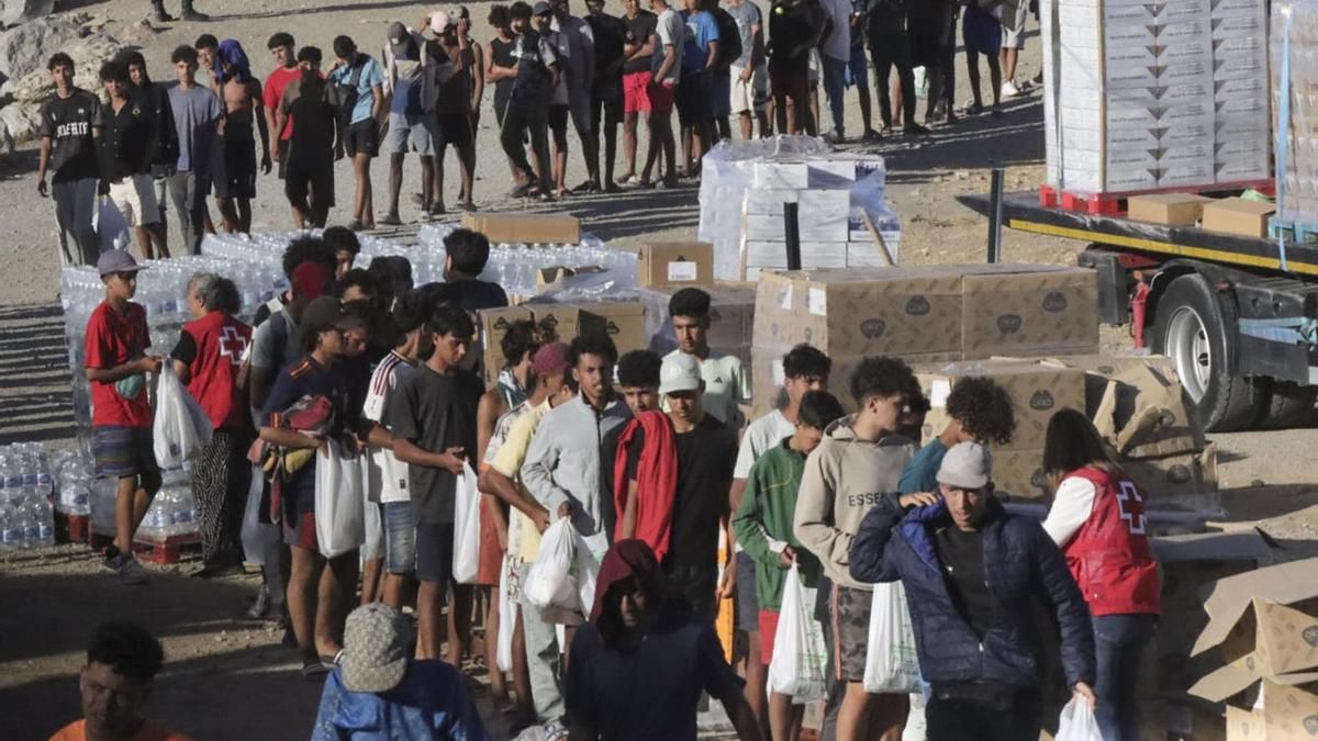 Reparto de alimentos por parte de Cruz Roja a los migrantes en la playa del Trampolín, el jueves en Ceuta. EFE/Reduan