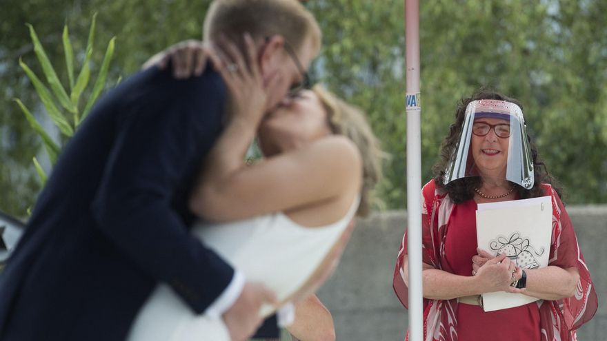 La comisionada de bodas Ruth Lipton, con una careta protectora, observa después de casarse con Nikki Alexis y Roni Jones.