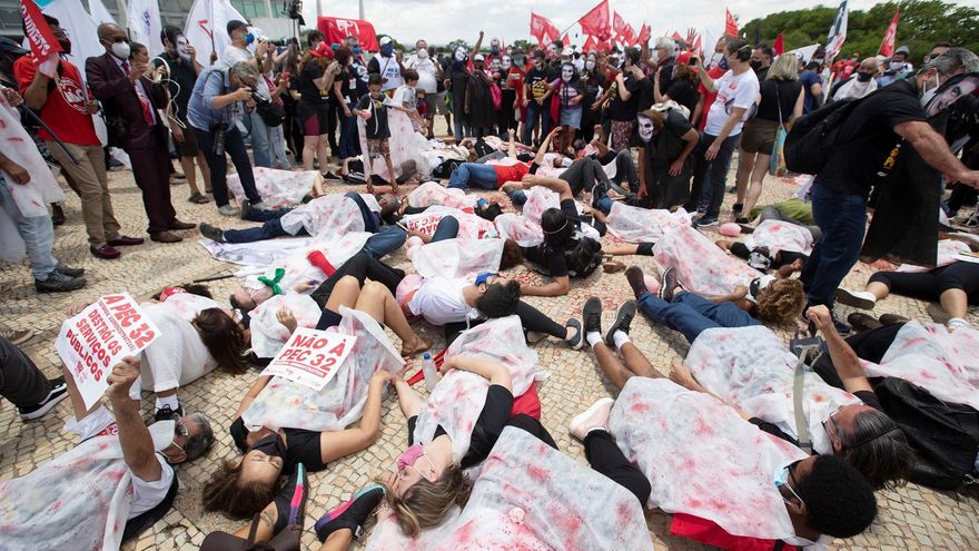Manifestantes se tumban al suelo para representar víctimas mortales de coronavirus durante una manifestación contra el presidente de Brasil, Jair Bolsonaro, y su manejo de la pandemia, hoy, en Brasilia (Brasil).