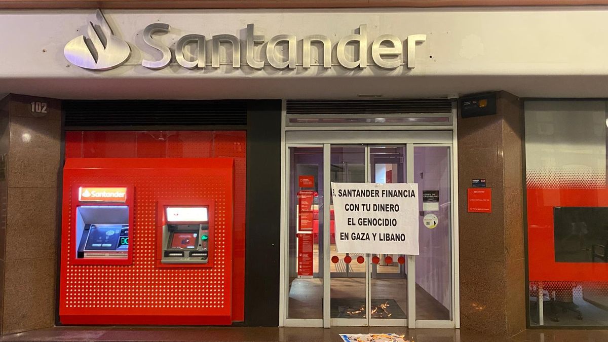 Activistas queman una bandera en una sede del banco Santander en Las Palmas de Gran Canaria.