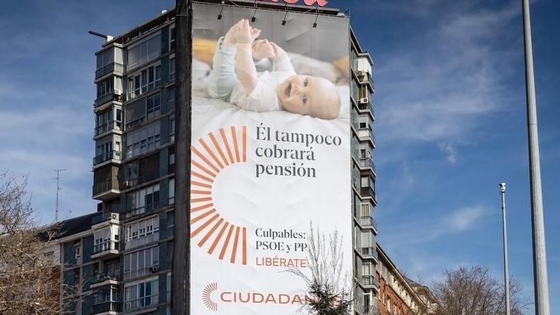 Ciudadanos despliega una lona para denunciar la "estafa intergeneracional" del sistema público de pensiones.