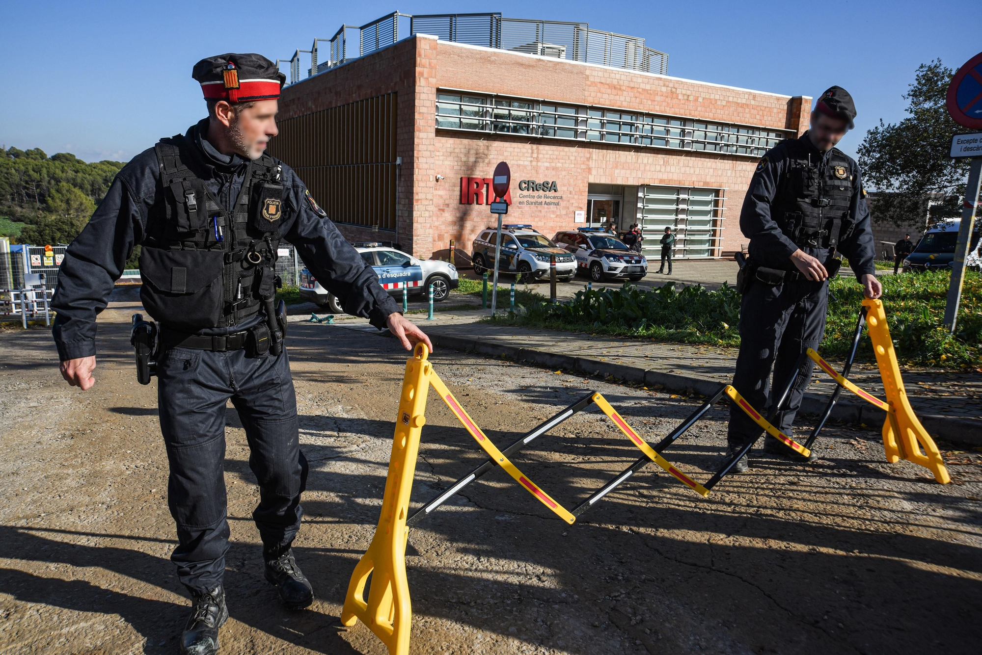 Dos agentes de los Mossos d'Esquadra acordonan una zona en el laboratorio del IRTA, a 18 de diciembre de 2025, en Cerdanyola, Barcelona, Catalunya (España).