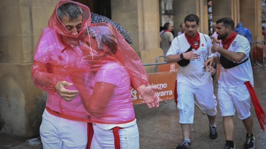 Dos personas se protegen de la intensa lluvia caída en Pamplona, donde han dado comienzo los Sanfermines 2022. EFE/Eloy Alonso