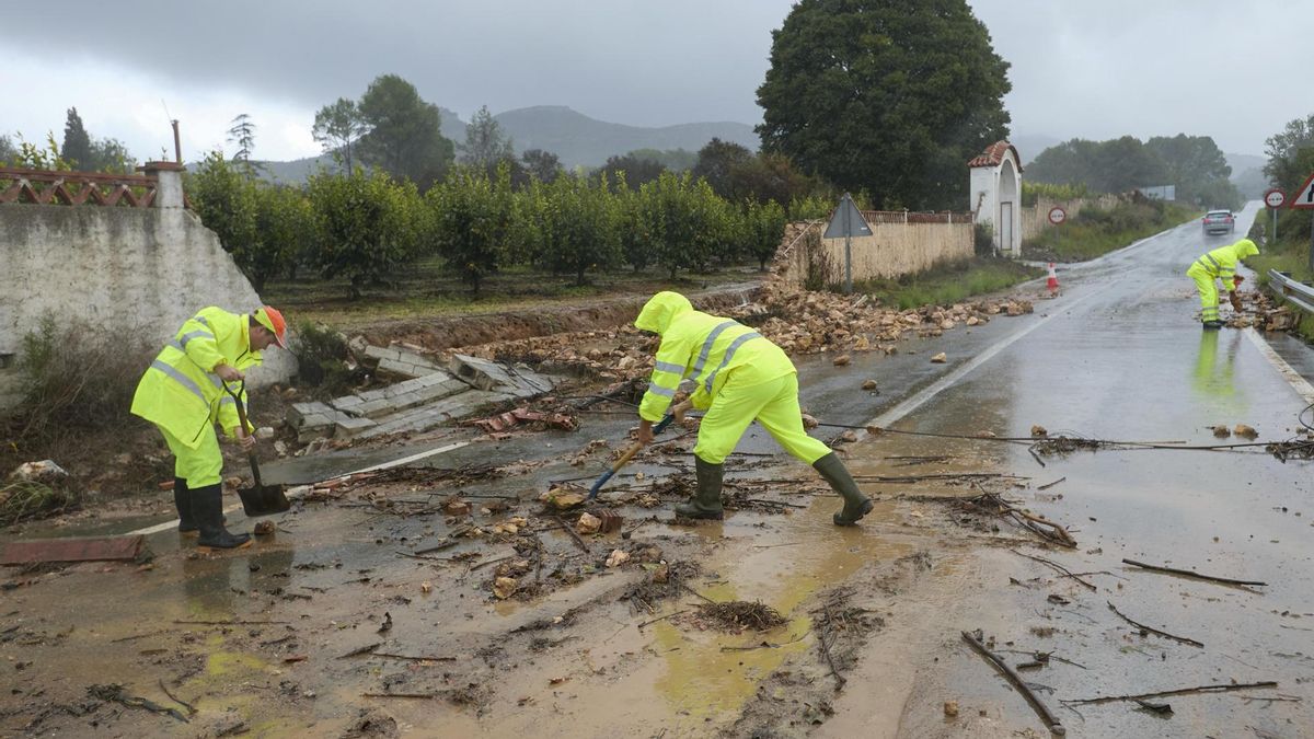 Unos operarios limpian la carretera de acceso a Manuel cortada debido a las lluvias torrenciales que afectan a la Comunitat Valenciana, y especialmente a la provincia de Valencia, en la que se ha establecido el aviso rojo