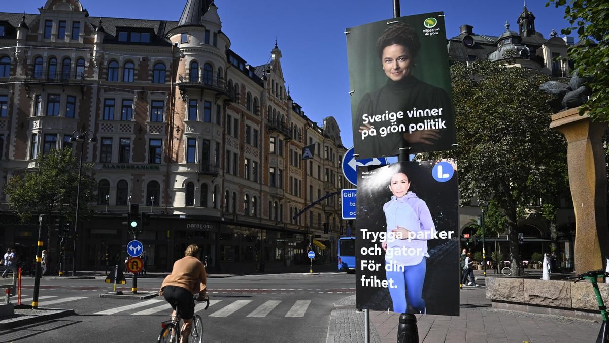 Una mujer pasa junto a carteles electorales del Partido Verde y del Partido Liberal ante las elecciones generales en Estocolmo.