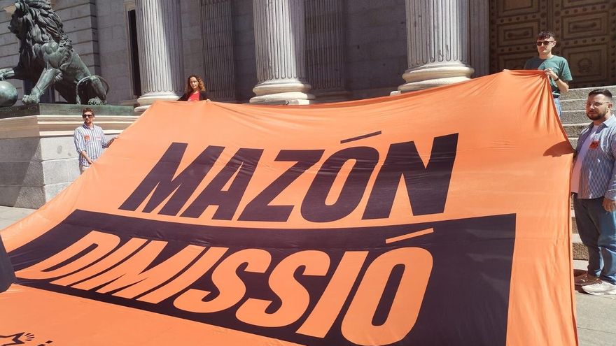 Jóvenes de Compromís despliegan una pancarta en la Puerta del Congreso exigiendo la dimisión de Mazón