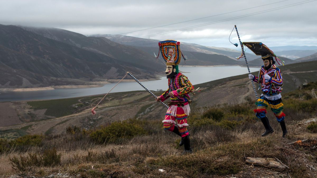Dos boteiros en Vilariño de Conso caminan por un paraje con el embalse de As Portas de fondo. 