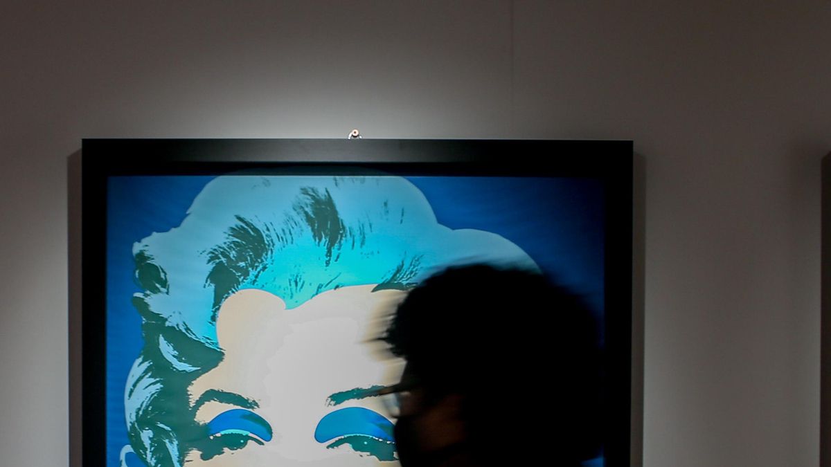 Una persona para por delante de un retrato de Marilyn Monroe,   en la inauguración de la exposición 'ANDY WARHOL SUPER POP', en el Palacio de Santa Bárbara, a 11 de febrero de 2022, en Madrid (España).