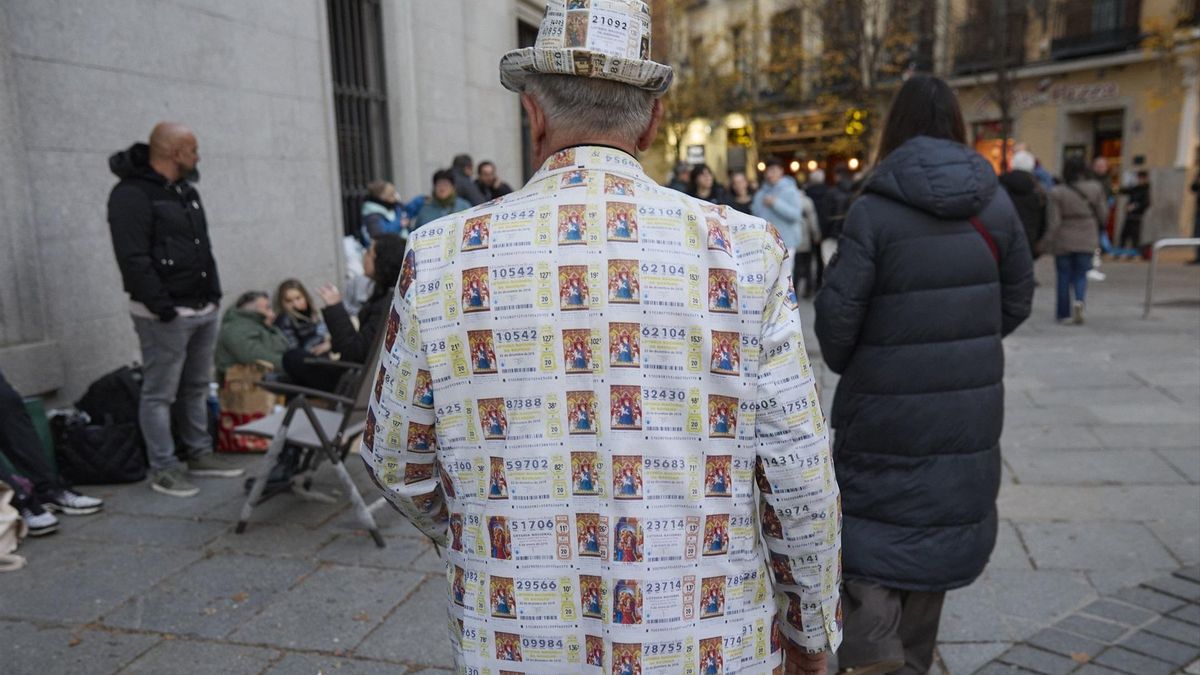 Un hombre con una chaqueta de décimos de lotería hace cola para entrar en el Sorteo de la Lotería de Navidad