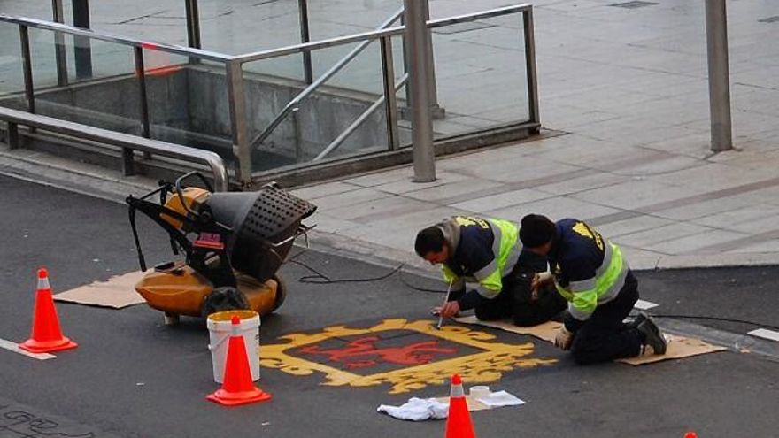 Los operarios pintando a brocha los 'tatuajes' de asfalto de Ordoño II. Foto: Uribe.