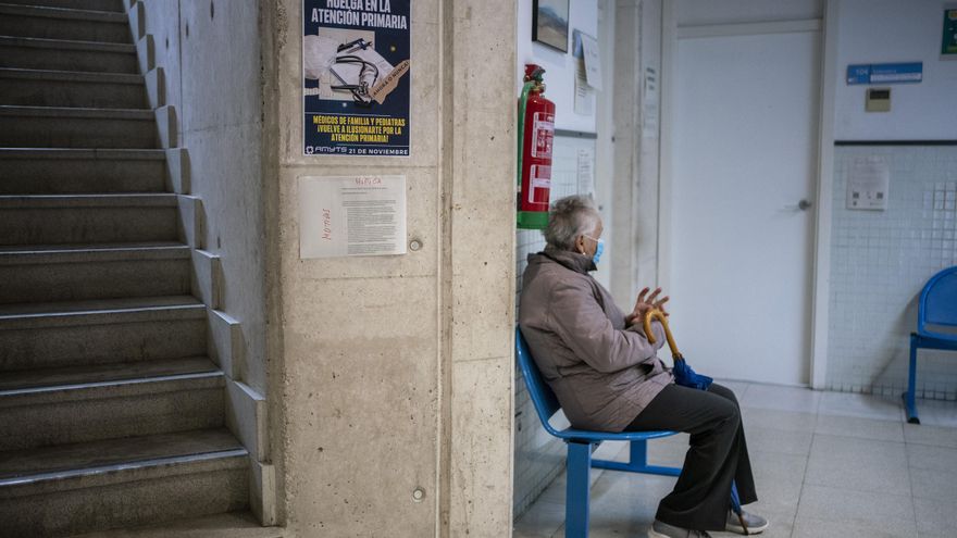 Una mujer espera en el centro de salud Numancia, donde se pueden ver carteles de la huelga.