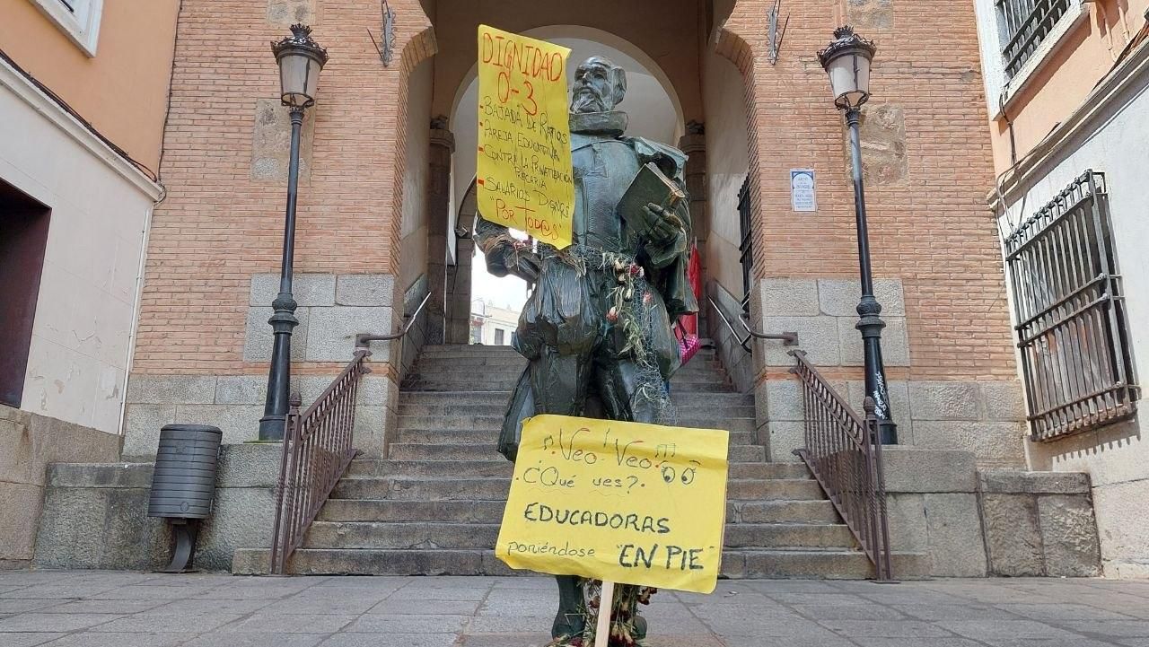 Estatua de Miguel de Cervantes, en Toledo, con dos pancartas de las concentraciones de las docentes de escuelas infantiles.