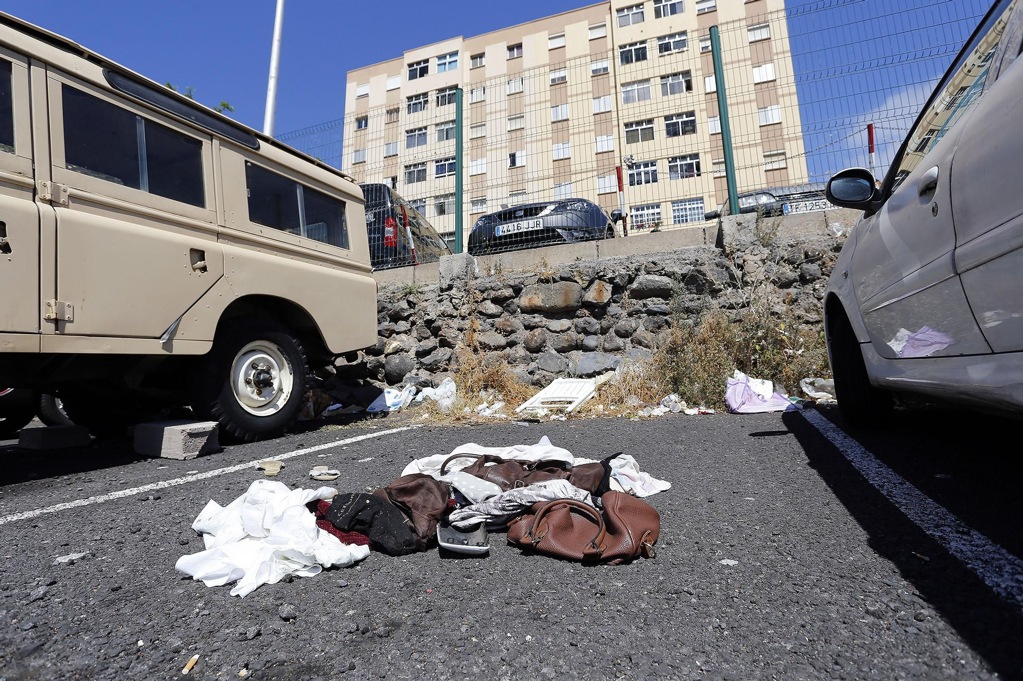 Restos de ropas dejados en el asfalto de una plaza de aparcamiento