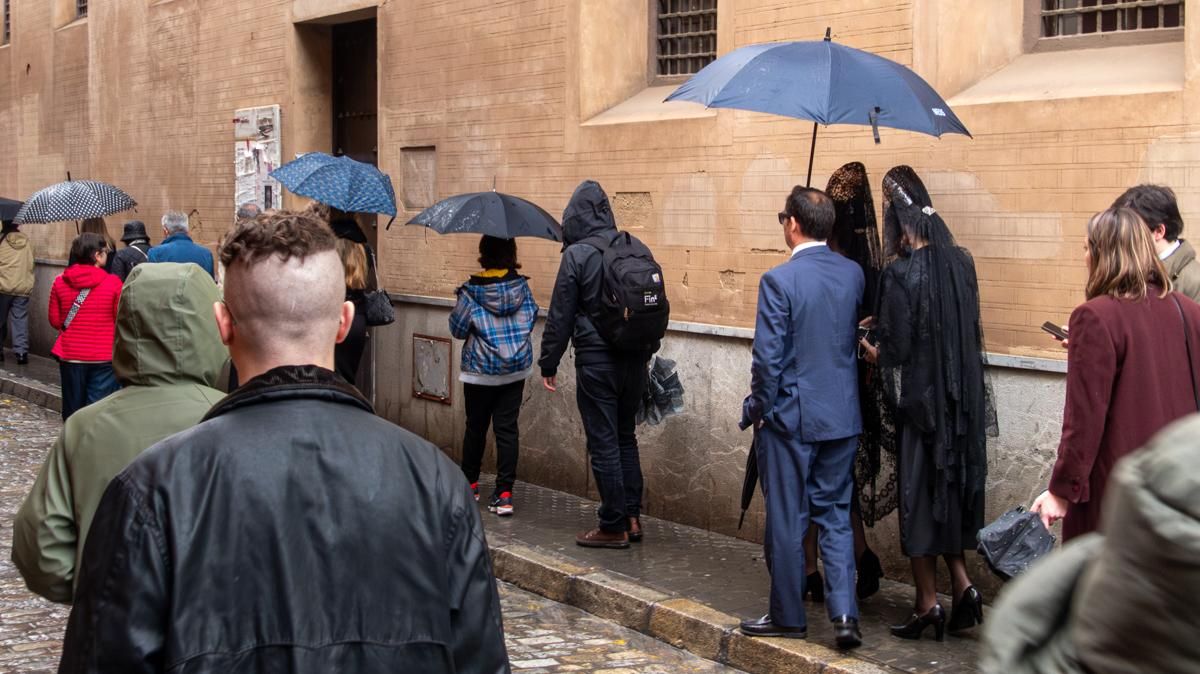 Mantillas protegiéndose de la lluvia en la cola de la Quinta Angustia