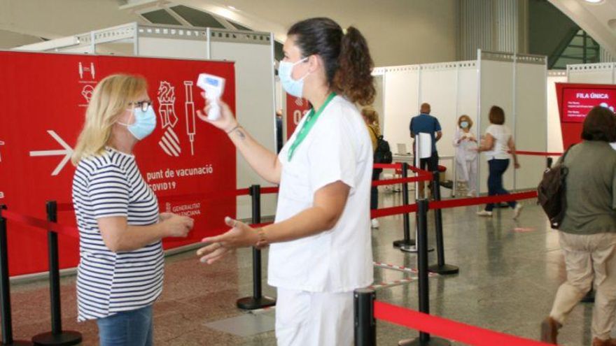 Una enfermera toma la temperatura a una ciudadana en el punto de vacunación contra el coronavirus en València.
