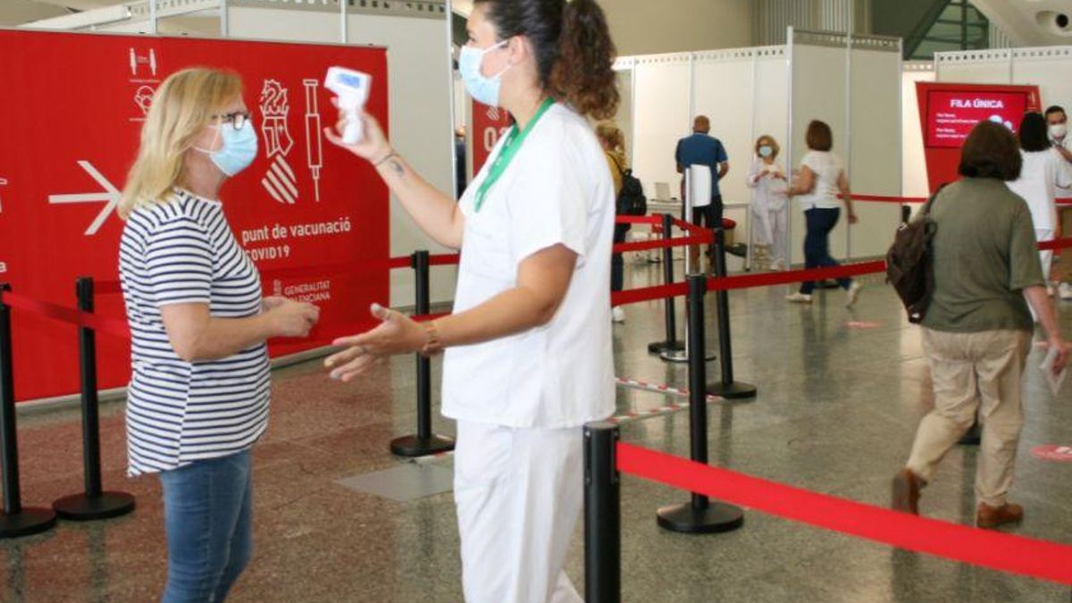 Una enfermera toma la temperatura a una ciudadana en el punto de vacunación contra el coronavirus en València.
