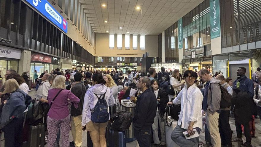 Pasajeros hacen cola en la estación de Santa Justa en Sevilla esta mañana, esperando poder coger un tren para llegar a sus destinos.