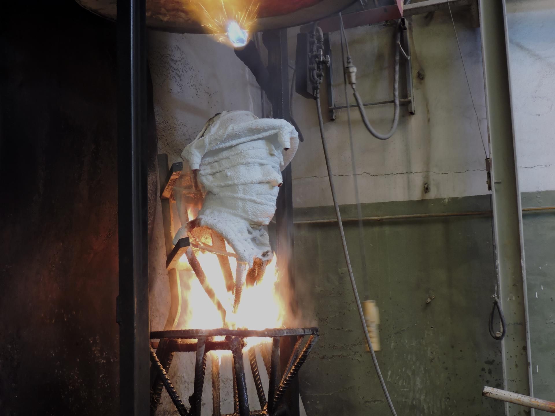Un molde de cascarilla cerámica se quema en fundición para albergar una pieza escultórica en bronce.