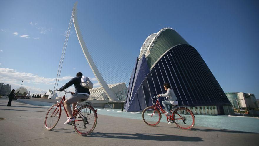 Dos ciclistas pasan por delante del Ágora de la Ciudad de las Artes y las Ciencias de València.