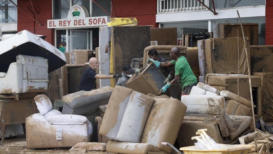 Varias personas sacan el mobiliario de una tienda de venta de sofás en Massanassa (Valencia), este miércoles.