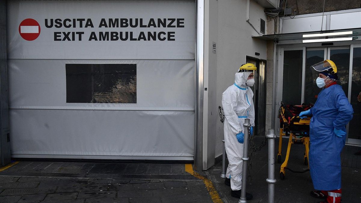 Health workers wearing protective suits and masks wait in front of the First Aid department entrance to the Galliera Hospital to receive patients in Genoa, Italy, 10 January 2022.