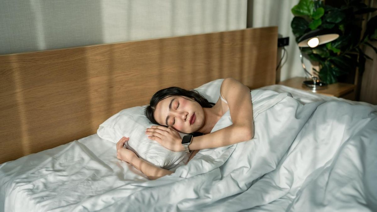 Una mujer duerme con el brazo bajo la almohada