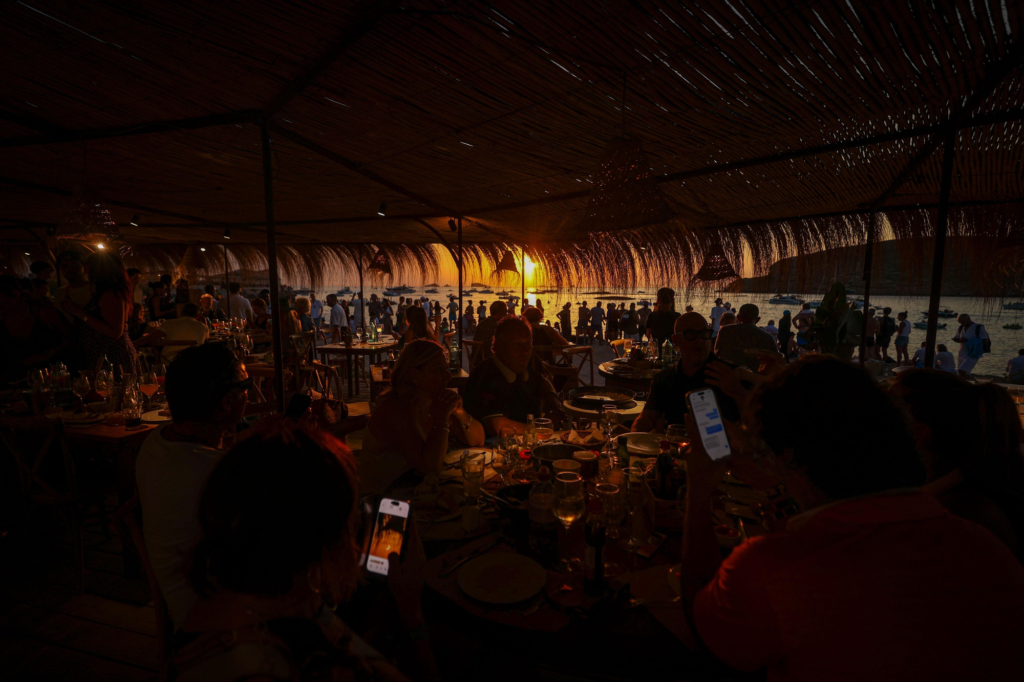 Desde las terrazas de los restaurantes y chiringuitos de la zona, los comensales interrumpen sus cenas para maravillarse con el atardecer astronómico