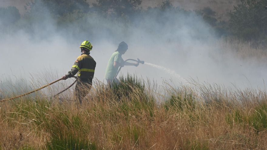 Bomberos forestales remojan una zona ante el avance del incendio de Murias de Ponjos (León).
