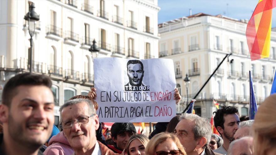 Un manifestante sujeta una pancarta del presidente del Gobierno en funciones durante una protesta contra la amnistía, en la Puerta del Sol, en Madrid.