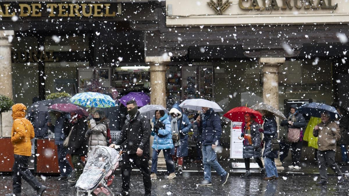 Varias personas caminan por una calle de Teruel durante la nevada este miércoles.