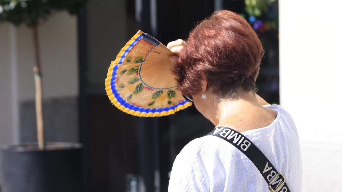 Una mujer se protege del sol con un abanico