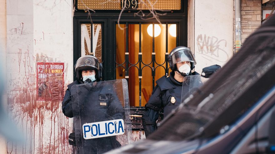 Dos agentes de la policía nacional aguardan en el exterior del edificio.