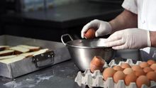 Un repostero casca huevos durante la elaboración de torrijas.