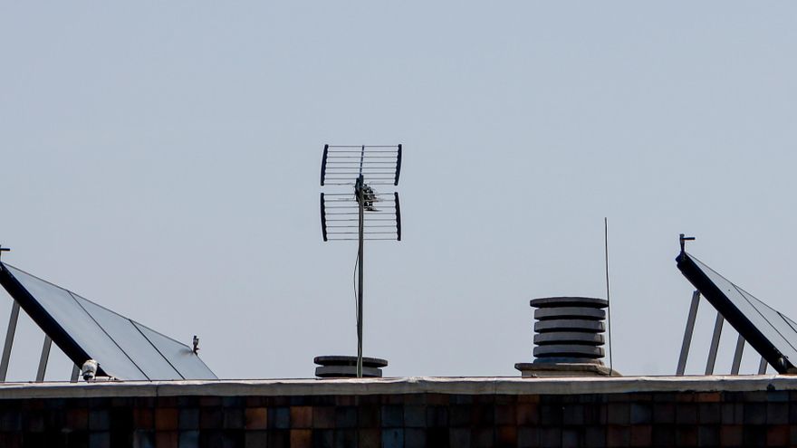 Paneles solares junto a una antena en el tejado de un edificio de Madrid.