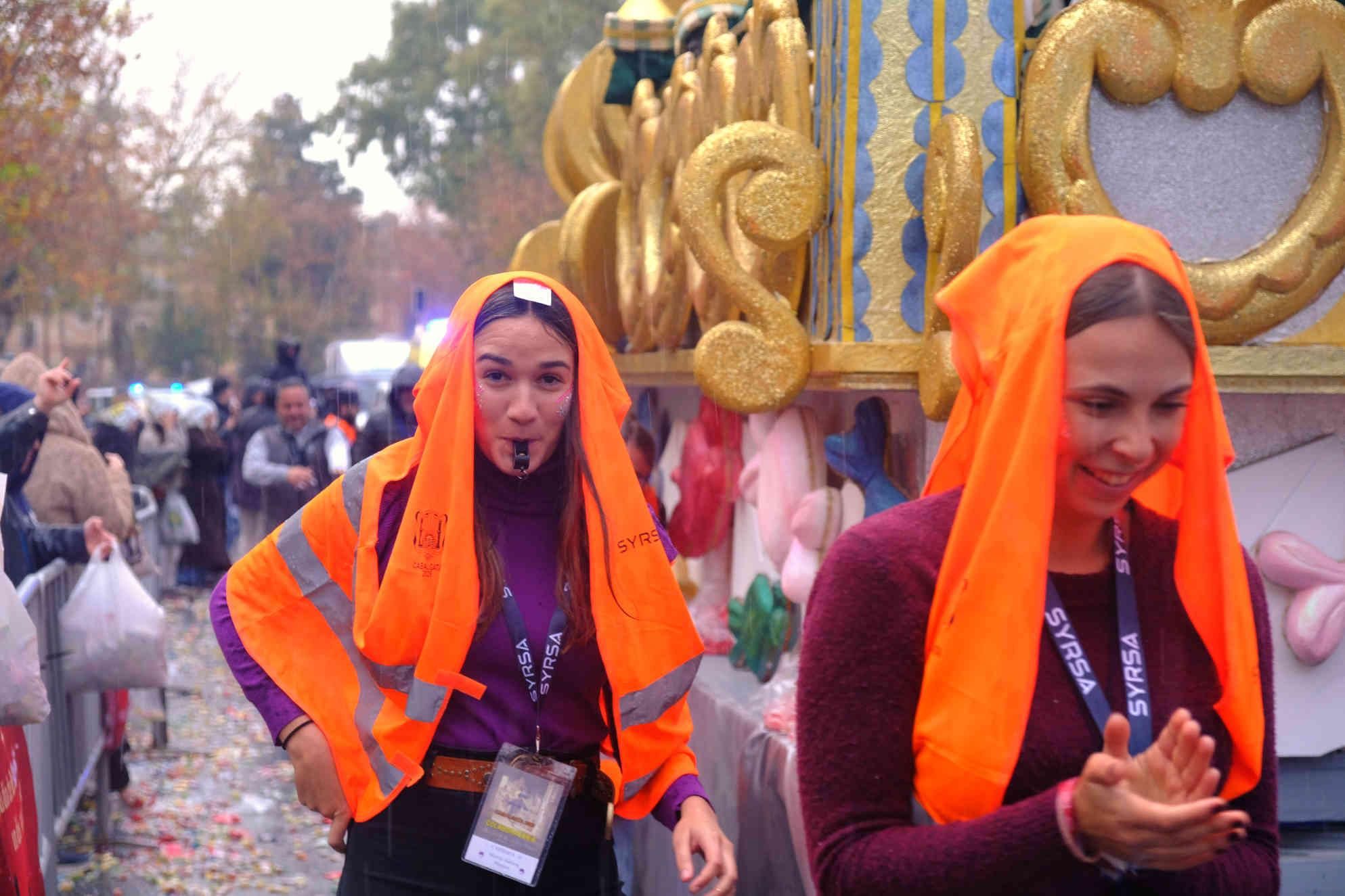 El personal de escolta de una carroza se protege como puede del agua