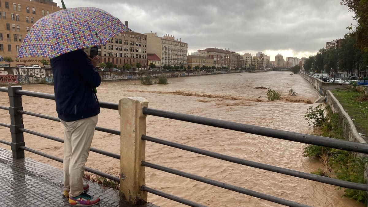 Un hombre observa el aspecto que presenta el río Guadalmedina a su paso por Málaga este miércoles en el que las fuertes lluvias y granizo que se registran están causando inundaciones y acumulación de grandes balsas en algunas de las principales avenidas de todos los distritos de la ciudad.