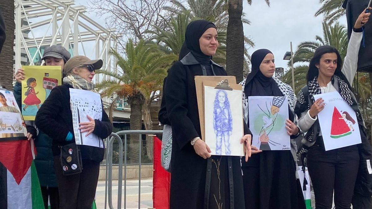 Wesam Hamada, madre de Hind Rajab, con el retrato de su hija, realizado por la artista María del Mar Gregorio y ampliado en un gigantesca lona 