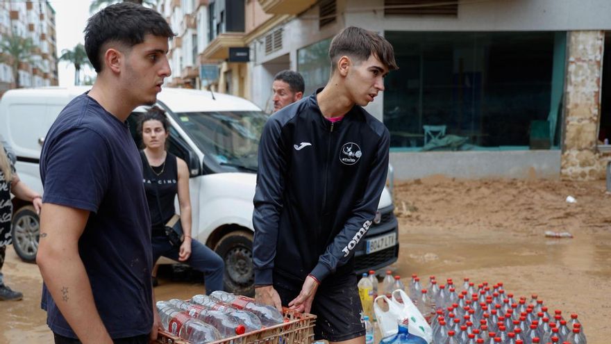 Varias personas reparten botellas de agua este jueves en Paiporta.