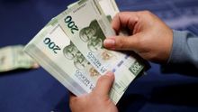 Una mujer muestra un billete de 200 pesos.