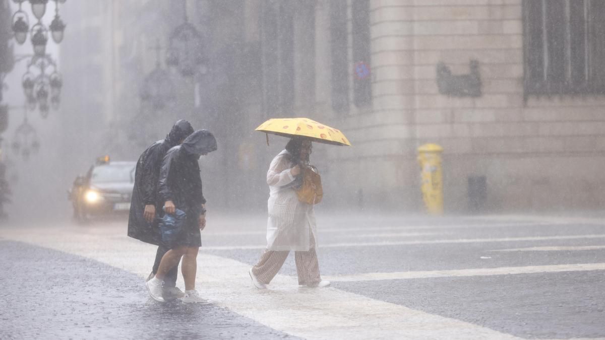 Personas se protegen de la lluvia este jueves en el centro de Barcelona.
