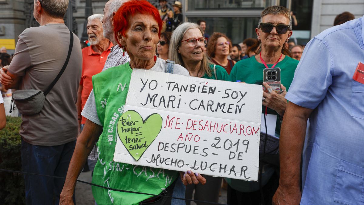 Una de las mujeres que asisten a la manifestación con un cartel en el que explica que también fue víctima de un desahucio