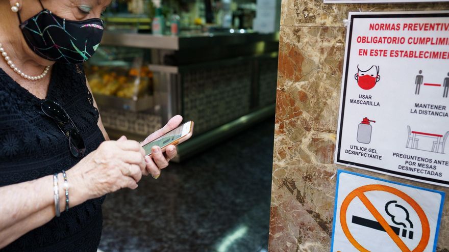 Una mujer busca en su móvil su certificado Covid momentos antes de acceder al interior de una cafetería de Santa Cruz de Tenerife.EFE/Ramón de la Rocha