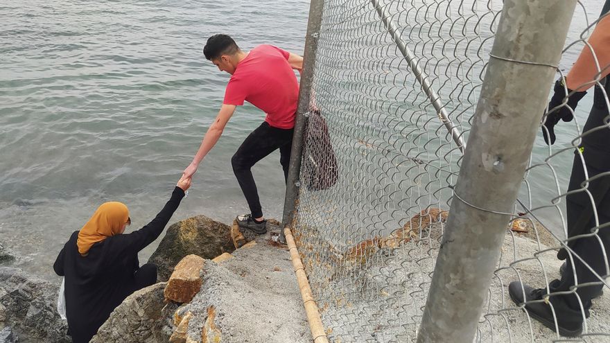 Dos inmigrantes escalan las rocas de uno de los espigones fronterizos de Ceuta, donde ayer se batió la cifra récord de llegada de inmigrantes a España en un solo día por vía marítima, contabilizando los 5000 marroquíes que según la delegación del gobierno en Ceuta han llegado a la ciudad autónoma. EFE/Reduan