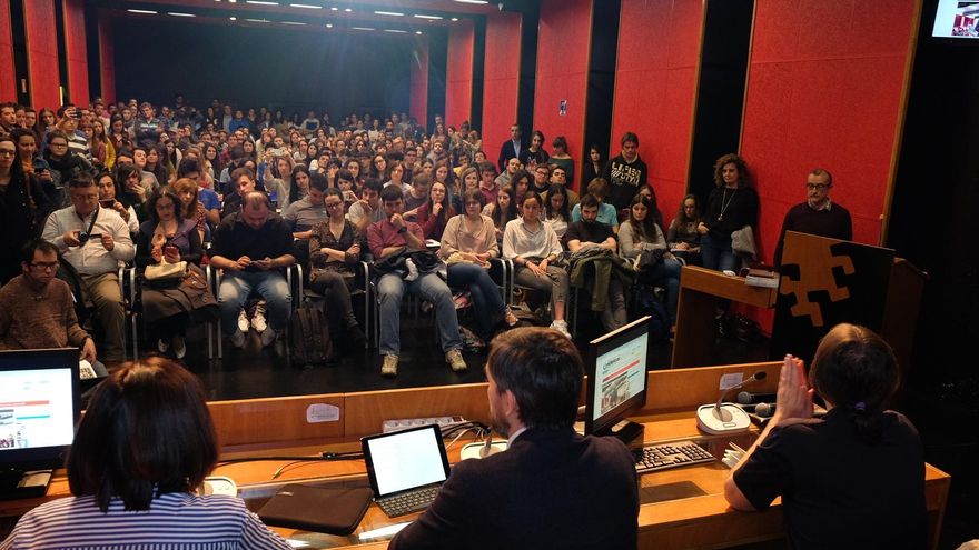 Escolar, en el medio, se dirige a un salón de actos abarrotado.