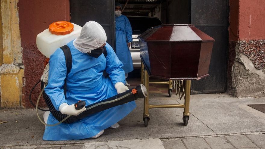 Un miembro de la Policía de Guatemala sanitiza el féretro de un hombre de 73 años, este lunes en Ciudad de Guatemala (Guatemala).