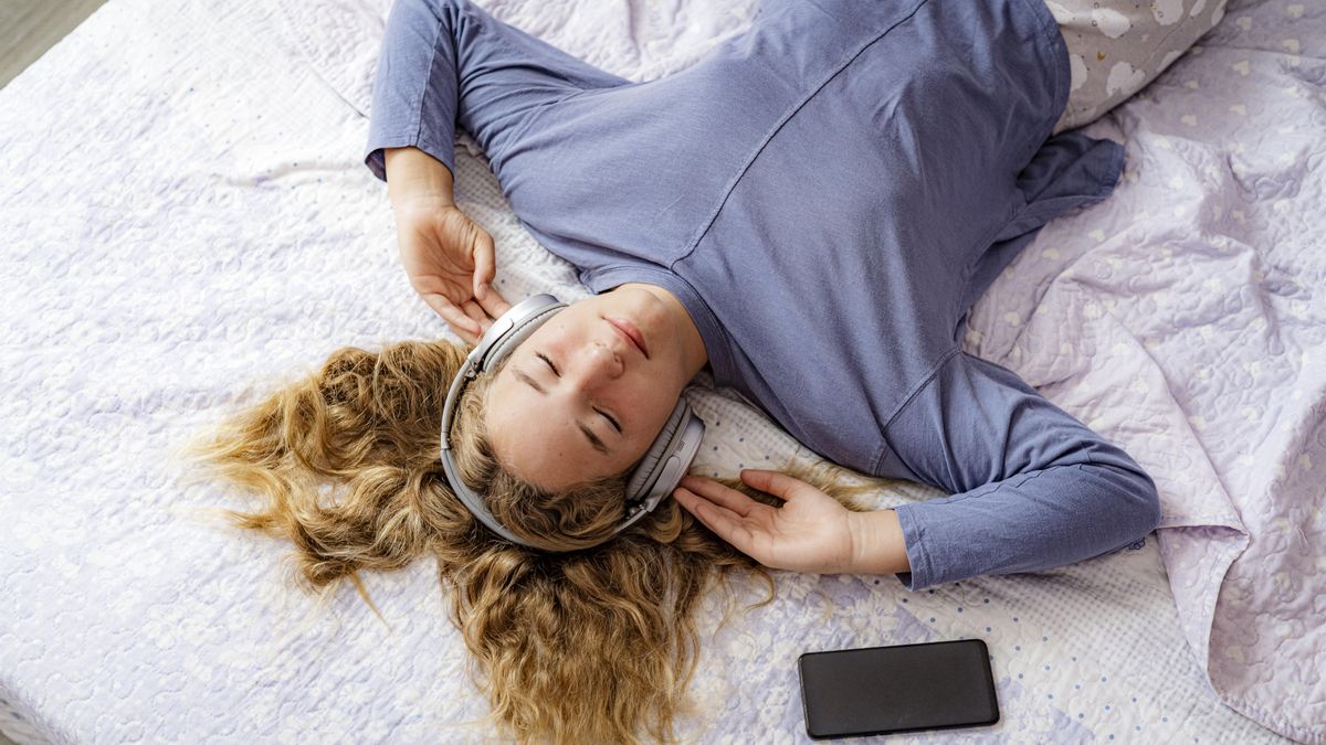 Joven utilizando auriculares en su habitación